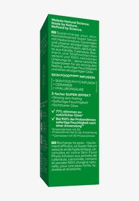 Scatola del Weleda Skin Food Super Serum con benefici del prodotto e ingredienti in tedesco e francese su uno sfondo verde.
