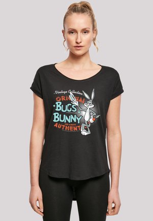 Svart T-skjorte med en avslappet passform, med en grafikk av Bugs Bunny og teksten "Original Bugs Bunny" i ulike farger. Korte ermer.