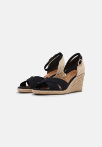 Námořnické wedges sandály s kříženými suknovými pásky. Podpatek obalený juty a také kotníkový pásek s kovovou přezkou. Design s otevřenou špičkou a texturovaný materiál.