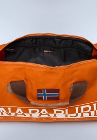 Oranssi kantokassi, jossa on teksturoitu pinta, ruskea kahva ja Norjan lipun kuvalla varustettu logo. Musta sisustus, jossa on vetoketjullinen tasku.