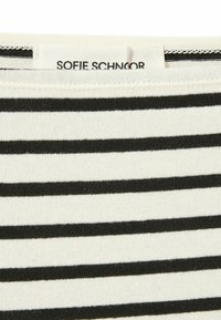 Černobílá látka s proužky a měkkou texturou. Na horním okraji je viditelná etiketa s nápisem "SOFIE SCHNOOR".