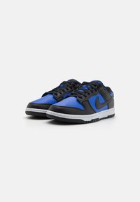 Sorte og blå atletik sneakers fremstillet i læder og syntetisk materiale, med en hvid mellemsål, perforeret tådesign og gummiydersål.