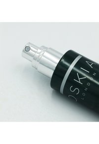 Sort kosmetik sprayflaske med en sølv pumpe. Har en klar knap til udskænkning. Etiketten inkluderer mærkenavnet i hvid tekst.