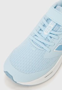 Baskets de course bleues avec une tige en mesh, surface texturée, design de lacets et col rembourré, accompagnées d'une semelle intermédiaire blanche et de marques sur le côté.
