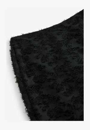 Must mustril õie tikandiga, millel on pehme tekstuur ja sile taust. Servad on korralikult lõpetatud.