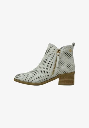 Botín de tobillo blanco perforado con cremallera lateral, punta redonda y tacón de bloque de madera. Textura suave con un patrón de cortes circulares.