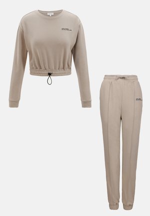 Beige cropped sweatshirt with a drawstring hem and black text; paired with matching joggers featuring an elastic waistband and sleek lines.