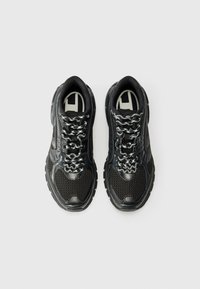 Baskets de sport noires avec des dessus en maille, des accents synthétiques texturés et des lacets à motifs noir et blanc. Comprend une semelle en caoutchouc durable.
