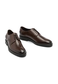 Bruine leren schoenen met een gladde afwerking, ronde neus en een laag profiel zwarte rubberen zool; beschikt over vetersluiting met vijf oogjes.
