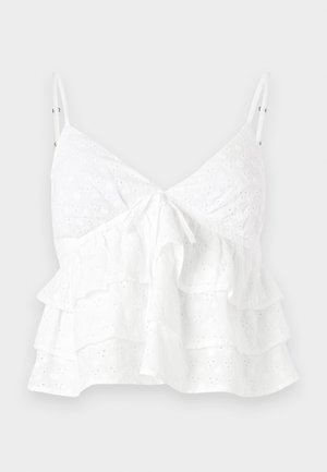 Haut sans manches blanc avec un décolleté en V, un détail de lien à l'avant et des volants en couches avec une broderie à oeillets sur l'ensemble.
