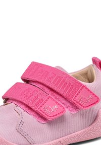 Zapatos rosa de velcro con parte superior de suave gamuza, que presentan dos correas anchas y una suela de goma texturizada con un patrón floral en relieve.
