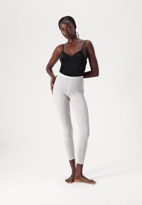 Black lace-trimmed camisole paired with light gray, heathered, high-waisted leggings. The leggings have a smooth texture and fitted design.