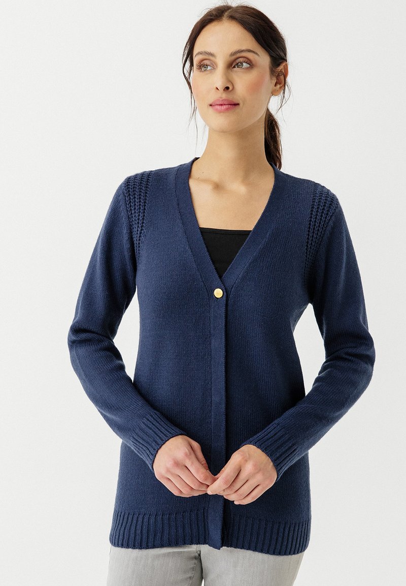 Cardigan lavorato a maglia blu navy con scollo a V, maniche lunghe, polsini a coste e un singolo bottone color oro davanti. Texture morbida e forma aderente.