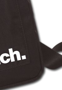 Sac en tissu noir avec une grande impression blanche "atteindre." à l'avant. Présente un matériau texturé et une sangle robuste pour le transport.