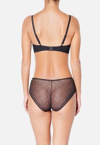 Soutien-gorge en dentelle noire avec bretelles réglables et fermeture à agrafes, assorti à un short transparent noir avec un motif en zigzag et des bords festonnés.