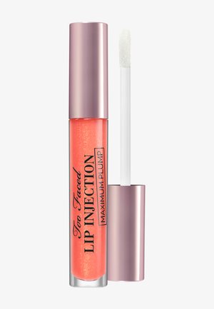 Glossy coral lip plumper avec paillettes dans un tube transparent et un capuchon métallique en or rose, applicateur baguette retiré.