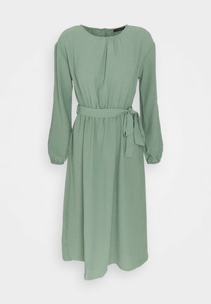 Robe à manches longues vert menthe avec un col rond, une taille cintrée et une ceinture nouée. Le tissu texturé offre une apparence douce et fluide.