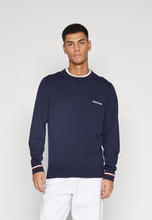 Maglione lavorato a maglia di colore blu navy con maniche lunghe, scollo rotondo e orlo a coste. Presenta un logo a contrasto sul petto e dettagli a righe sui polsini.
