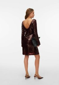 Burgunderfarget paljettkjole med lange ermer, dyp V-rygg og lengde over kneet. Kombinert med en svart clutch og brune slingback hæler.