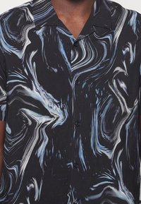 Short-sleeve button-up shirt featuring a black fabric with swirling blue and white marbled patterns, smooth texture, and a collar.