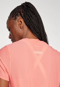 Lehká, prodyšná růžová sportovní tričko s texturovanou tkaninou. Obsahuje logo na zádech a minimalistický design.