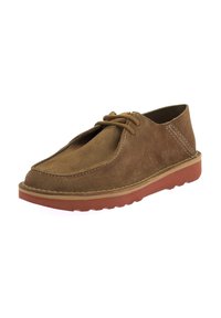 Scarpa in camoscio marrone con punta tondeggiante, due asole per i lacci, cuciture beige e suola in gomma rossa texturizzata. Design leggero con accenti minimi.