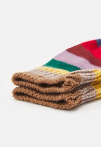 Meias de malha dobradas com riscas coloridas, deitadas sobre uma superfície branca, exibindo uma textura canelada e punhos castanhos.