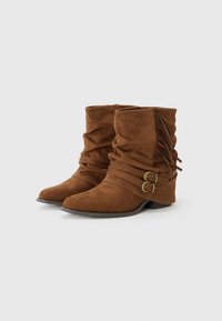 Brown suede ankle boots with a slouched design, featuring two buckled straps and side fringe detail. Low, contoured heel.