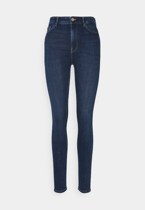 Jean skinny bleu foncé taille haute avec bouton frontal, fermeture éclair et design à cinq poches sur fond blanc uni.
