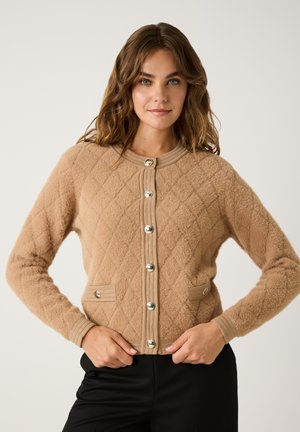 Tan, geweven cardigan gemaakt van zacht materiaal. Voorzien van zilveren knopen, geribde manchetten en opgestikte zakken. Klassieke ronde halslijn.