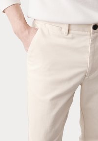 Lichtbeige op maat gemaakte broeken van zachte stof, met zijzakken, een gladde textuur en een lage taille met een knoopsluiting.