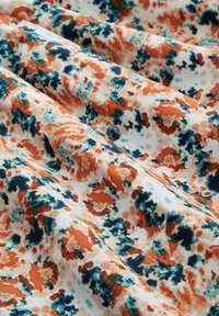 Tessuto multicolore con un motivo floreale astratto che presenta arancione, verde acqua e blu navy su uno sfondo bianco, con una texture liscia.