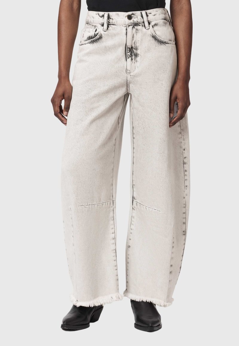 Wide-leg faded white jeans with frayed hems worn with black heeled boots and a black top, shown from waist to feet.