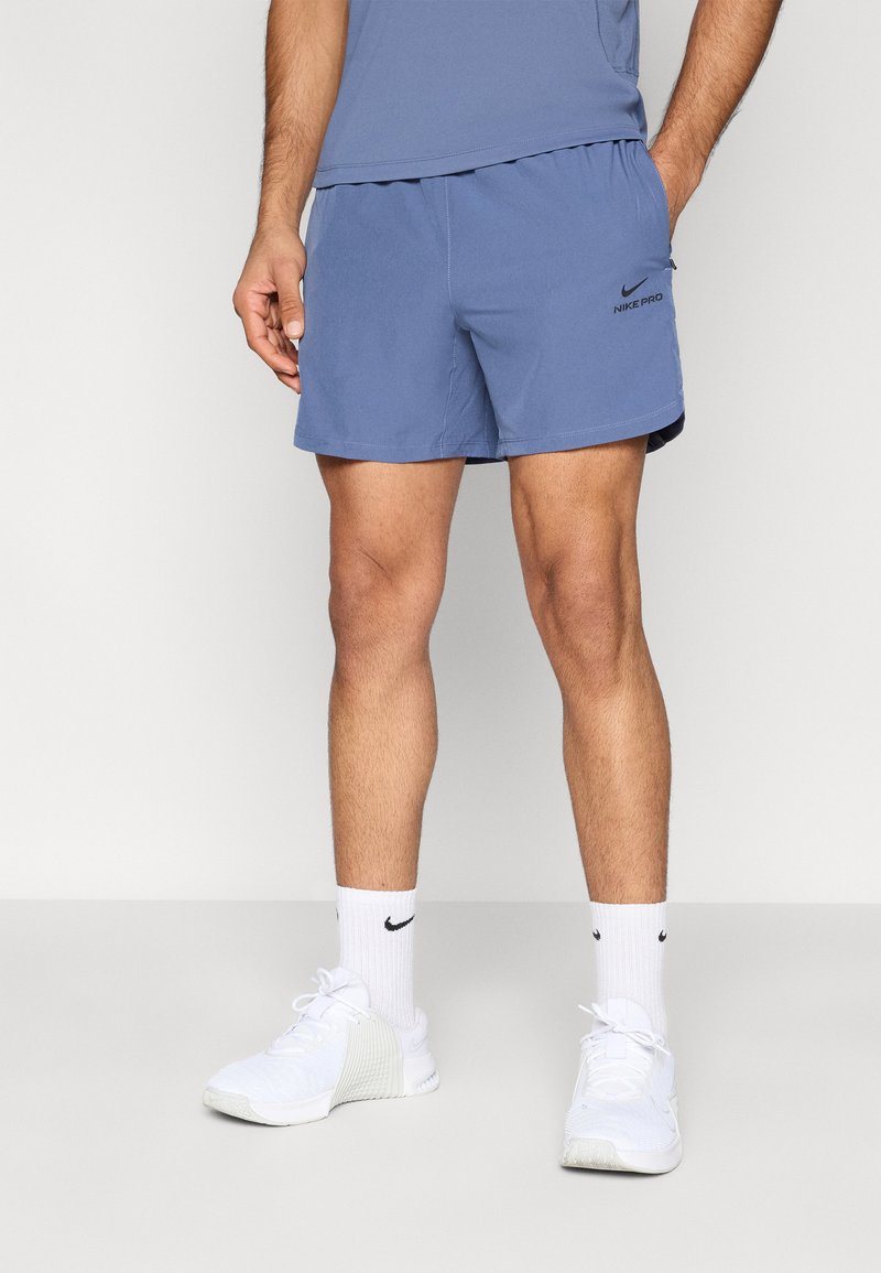 Ανοιχτό μπλε σορτσάκι Nike Pro από μαλακό ύφασμα, με ελαστική μέση και μικρό μαύρο λογότυπο. Συνδυασμένο με λευκά αθλητικά παπούτσια και κάλτσες.