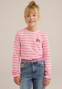 Růžové tričko s dlouhými rukávy a vodorovnými pruhy, zdobené výšivkou kolečkového brusle. V kombinaci s vysokými modrými džínami a růžovým páskem.