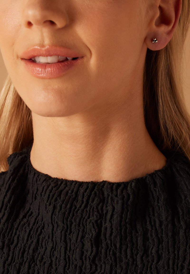 Boucles d'oreilles en argent au design minimaliste, avec un dessus noire texturée. Fini lisse et petite taille complètent le look.