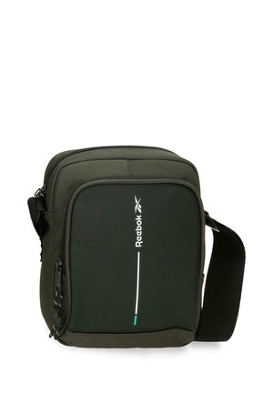 Pequeño bolso bandolera rectangular de color verde oscuro con bolsillo delantero con cremallera y asa negra ajustable, con la marca y logo vertical de Reebok.