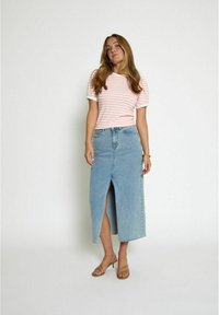 Rozā un baltu svītrainu T-kreklu ar īsām piedurknēm apvienojot ar gaiši zilu džinsu midi svārku ar priekšējo šķēlumu, valkājot gaišās brūnās sandales.