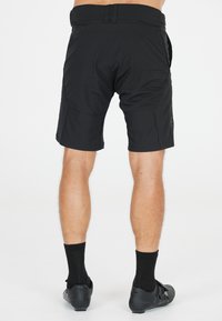 Schwarze Radshorts mit strukturiertem Finish, ausgestattet mit einem glatten Bund, Seitentaschen und einem knielangen Design. Verstellbarer Bund vorhanden.