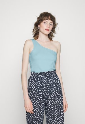 Top azul claro de um ombro feito de um tecido suave; combinado com calças azul-marinho com um padrão floral branco e um cós elástico.