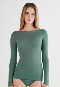 T-shirt à manches longues en tissu vert doux, avec un décolleté plongeant large et une coupe slim, offrant une texture lisse et un minimum de détails.
