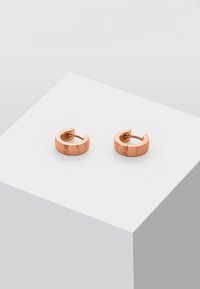 Orecchini a cerchio in oro rosa con una finitura liscia e lucida e un design minimalista. Ogni orecchino presenta una chiusura a cerniera sicura.