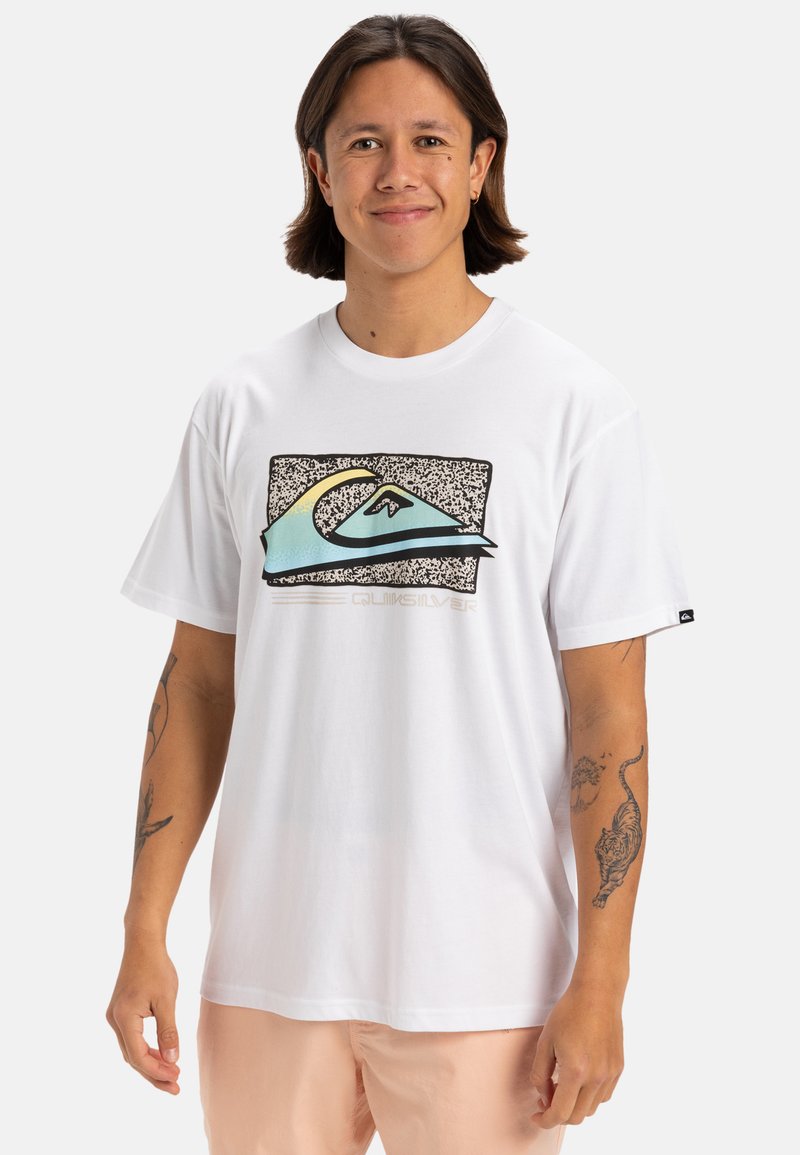 Camiseta de algodón blanca con un gráfico de olas multicolores sobre un fondo de patrón en blanco y negro, con el texto "Quiksilver" debajo.
