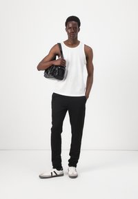 Svart veske med skinnende tekstur, hvit ribbestrikket tank topp, svarte bukser og grå sneakers med svarte striper. Enkel design, casual antrekk.