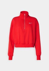 Röd långärmad croppad sweatshirt med dragkedja i kragen och en liten vit Nike swoosh-logga på bröstet.