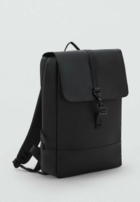 Zaino nero con finitura liscia e opaca, chiusura a pattina, fibbia frontale e spallacci in rete. Design minimalista con una silhouette elegante.