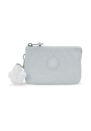 Lys grå stofpung med lynlås, rund Kipling-logo og lille hvid, fluffy abe-nøglering fastgjort.