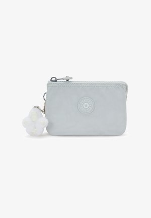 Bolsa de tela gris claro con cremallera, con logo redondo de Kipling y un pequeño llavero de mono blanco y esponjoso adjunto.