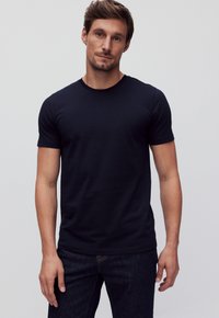 Heren navy blauwe t-shirt met korte mouwen van katoen, voorzien van een ronde hals en een slim fit, gecombineerd met donkere denim jeans.