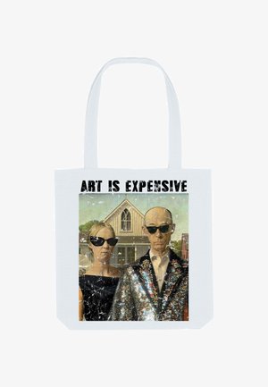 Due persone con occhiali da sole neri e abbigliamento formale si trovano di fronte a una fattoria con la scritta "L'ARTE È COSTOSA" sopra di loro.